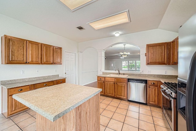 1506 Willow Bluff Dr, Pflugerville, TX 78660 - kitchen featuring appliances with stainless steel finishes, ornate columns, arched walkways, and brown cabinetry