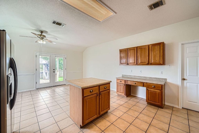 1506 Willow Bluff Dr, Pflugerville, TX 78660 - kitchen with stainless steel refrigerator with ice dispenser, brown cabinetry, a textured ceiling, french doors, and light tile patterned floors