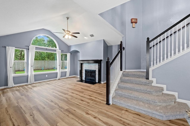 9105 Trickle Trace Trl, Round Rock, TX 78681 - unfurnished living room featuring a ceiling fan, a fireplace, wood finished floors, stairs, and arched walkways