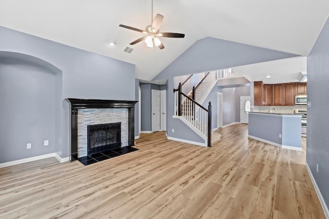 9105 Trickle Trace Trl, Round Rock, TX 78681 - unfurnished living room featuring ceiling fan, light wood finished floors, stairs, a fireplace, and high vaulted ceiling