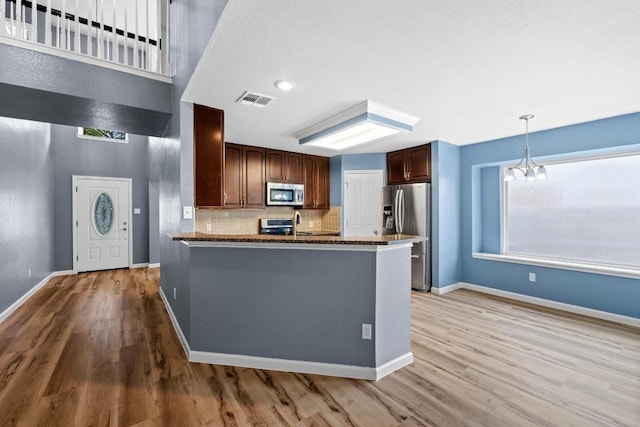 9105 Trickle Trace Trl, Round Rock, TX 78681 - kitchen with stainless steel appliances, light wood-type flooring, a chandelier, backsplash, and a peninsula
