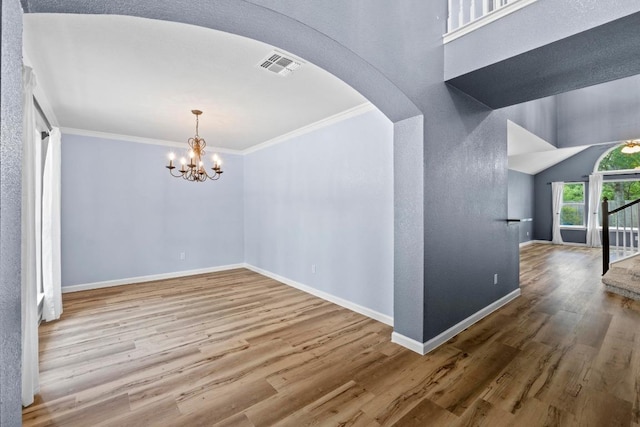 9105 Trickle Trace Trl, Round Rock, TX 78681 - unfurnished dining area with arched walkways, wood finished floors, ornamental molding, and a chandelier