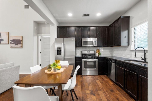 2101 Rivers Edge Way Unit 17, Austin, TX 78741 - kitchen featuring appliances with stainless steel finishes, dark countertops, dark wood finished floors, backsplash, and dark brown cabinetry