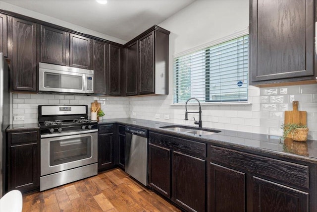 2101 Rivers Edge Way Unit 17, Austin, TX 78741 - kitchen with appliances with stainless steel finishes, dark stone counters, dark brown cabinets, wood finished floors, and tasteful backsplash