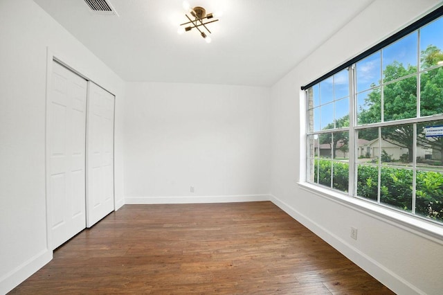 3013 Wavecrest Blvd, Austin, TX 78728 - unfurnished bedroom featuring multiple windows, dark wood finished floors, a closet, and a chandelier
