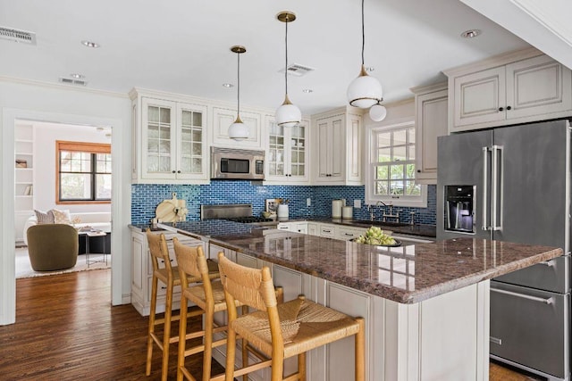 1118 Reagan Ter, Austin, TX 78704 - kitchen with stainless steel appliances, decorative backsplash, a center island, glass insert cabinets, and a breakfast bar area