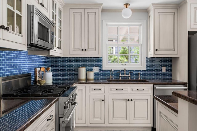 1118 Reagan Ter, Austin, TX 78704 - kitchen with stainless steel appliances, decorative backsplash, ornamental molding, glass insert cabinets, and white cabinetry