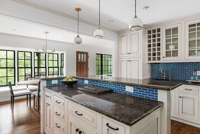 1118 Reagan Ter, Austin, TX 78704 - kitchen featuring tasteful backsplash, dark wood finished floors, glass insert cabinets, ornamental molding, and hanging light fixtures