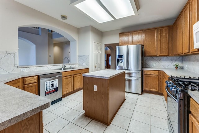 601 Indian Run Dr, Pflugerville, TX 78660 - kitchen with appliances with stainless steel finishes, backsplash, brown cabinetry, a center island, and light countertops