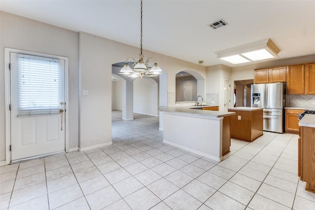 601 Indian Run Dr, Pflugerville, TX 78660 - kitchen with stainless steel fridge with ice dispenser, arched walkways, light countertops, a chandelier, and light tile patterned floors