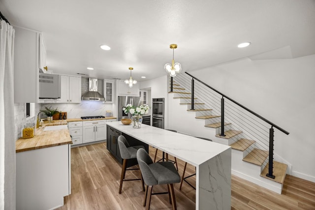 3704 Laurel Ledge Ln, Austin, TX 78731 - kitchen with appliances with stainless steel finishes, wall chimney range hood, a center island, white cabinets, and recessed lighting