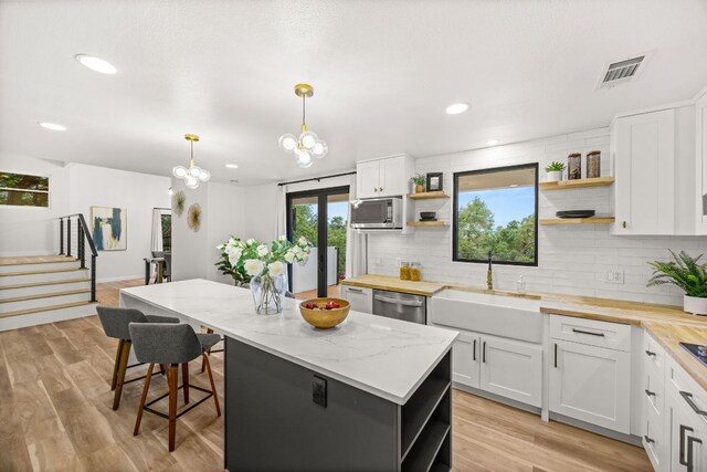 3704 Laurel Ledge Ln, Austin, TX 78731 - kitchen featuring open shelves, stainless steel appliances, decorative backsplash, a kitchen island, and white cabinetry