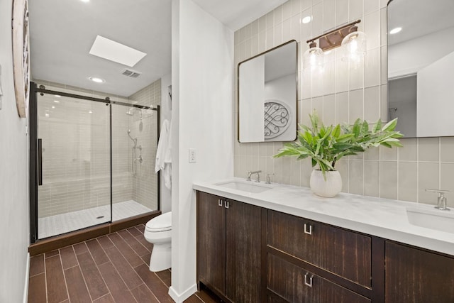 3704 Laurel Ledge Ln, Austin, TX 78731 - bathroom featuring a stall shower, double vanity, a skylight, decorative backsplash, and wood finished floors