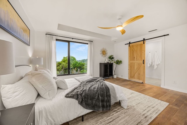 3704 Laurel Ledge Ln, Austin, TX 78731 - bedroom with a barn door, wood finished floors, and a ceiling fan