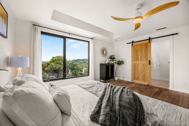 3704 Laurel Ledge Ln, Austin, TX 78731 - bedroom featuring a barn door, wood finished floors, a tray ceiling, and a ceiling fan