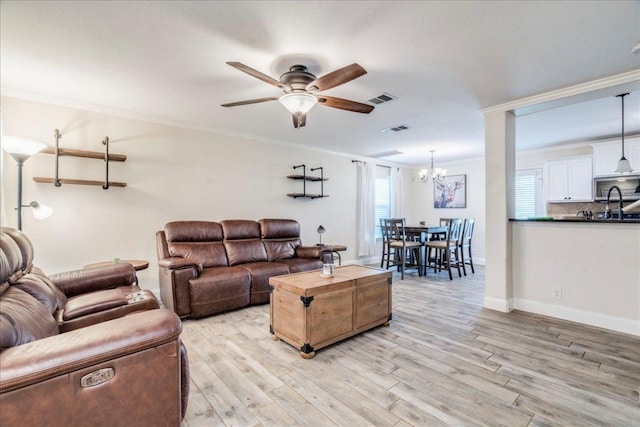 217 Adriana Ln, Hutto, TX 78634 - living room featuring crown molding, ceiling fan, light wood-type flooring, and a chandelier
