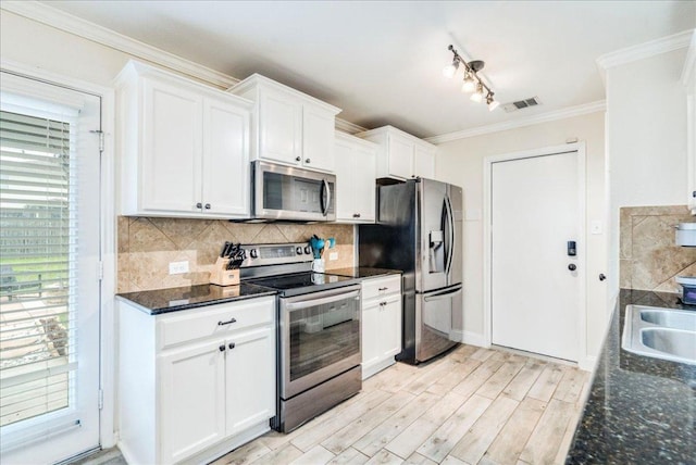 217 Adriana Ln, Hutto, TX 78634 - kitchen featuring appliances with stainless steel finishes, plenty of natural light, white cabinets, crown molding, and decorative backsplash