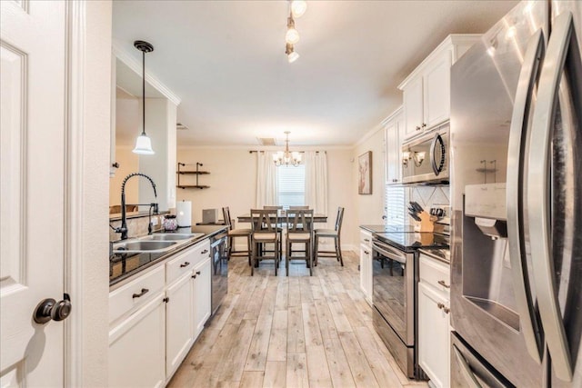 217 Adriana Ln, Hutto, TX 78634 - kitchen featuring appliances with stainless steel finishes, dark countertops, a chandelier, white cabinetry, and crown molding