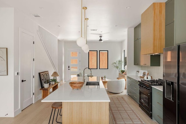 505 Philco Dr Unit 3, Austin, TX 78745 - kitchen with stainless steel fridge, black gas range oven, light wood finished floors, light countertops, and a kitchen bar