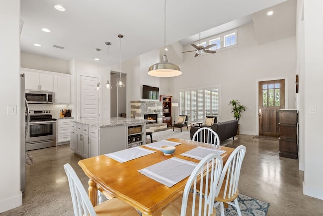 503 Alva Dr, Spicewood, TX 78669 - dining space featuring healthy amount of natural light, a stone fireplace, ceiling fan, recessed lighting, and finished concrete flooring