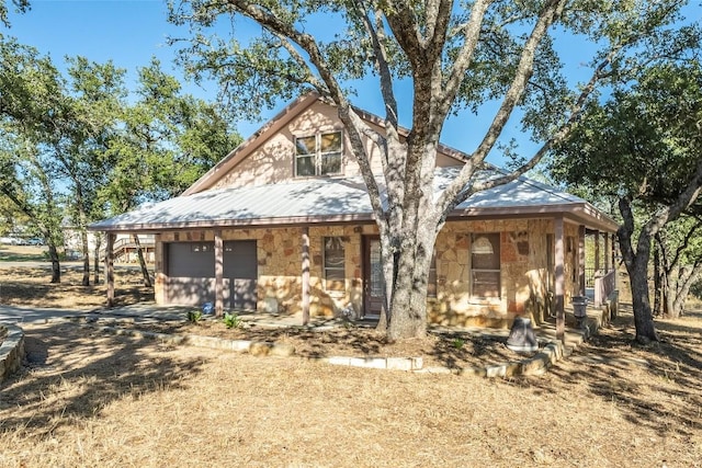 103 Rolling Hills Dr, Spicewood, TX 78669 - view of front of property featuring stone siding, a metal roof, and a garage