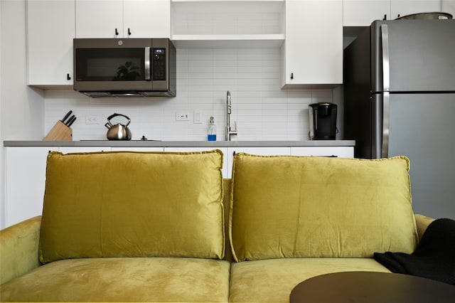 49 Navasota St Unit 216, Austin, TX 78702 - kitchen with appliances with stainless steel finishes, white cabinetry, and tasteful backsplash