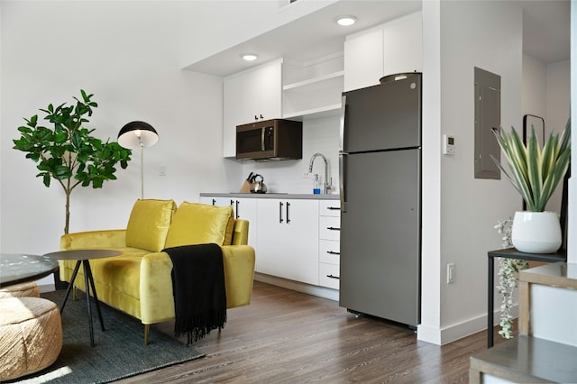 49 Navasota St Unit 216, Austin, TX 78702 - kitchen featuring freestanding refrigerator, stainless steel microwave, white cabinets, dark wood-style floors, and decorative backsplash
