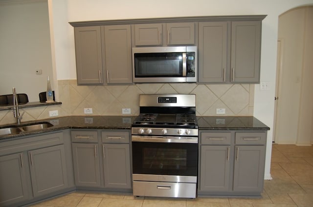 4216 Veiled Falls Dr, Pflugerville, TX 78660 - kitchen with appliances with stainless steel finishes, gray cabinets, dark stone countertops, decorative backsplash, and light tile patterned floors