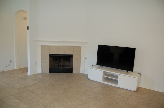 4216 Veiled Falls Dr, Pflugerville, TX 78660 - unfurnished living room with arched walkways, a tiled fireplace, and light tile patterned floors