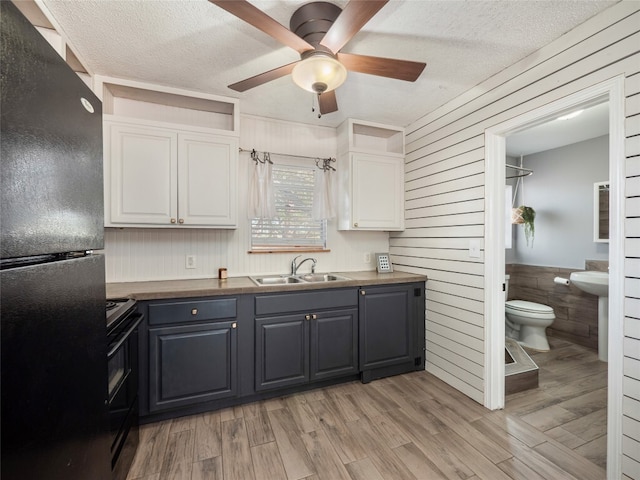 3908 Boat Dock Rd, Lago Vista, TX 78645 - kitchen with black appliances, white cabinetry, a ceiling fan, light wood-type flooring, and a textured ceiling