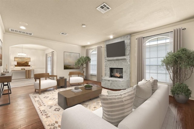 2908 Arbor Ct, Round Rock, TX 78681 - living area featuring arched walkways, a fireplace, wood-type flooring, recessed lighting, and crown molding