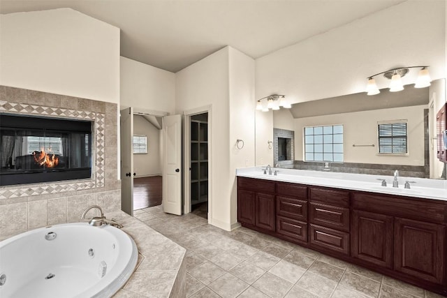 2908 Arbor Ct, Round Rock, TX 78681 - full bath with double vanity, a jetted tub, tile patterned floors, and a tiled fireplace