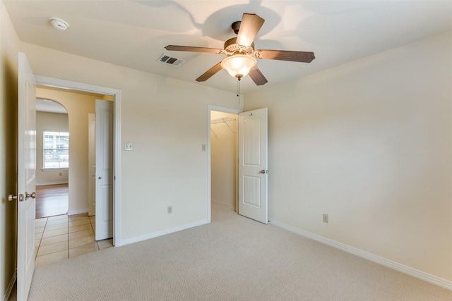 13604 Caldwell Dr Unit 72, Austin, TX 78750 - unfurnished bedroom featuring light carpet, light tile patterned flooring, ceiling fan, and a walk in closet