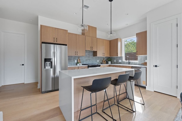 6406 Cannonleague Dr Unit 2, Austin, TX 78745 - kitchen with stainless steel appliances, light wood-style flooring, decorative backsplash, light countertops, and a kitchen island