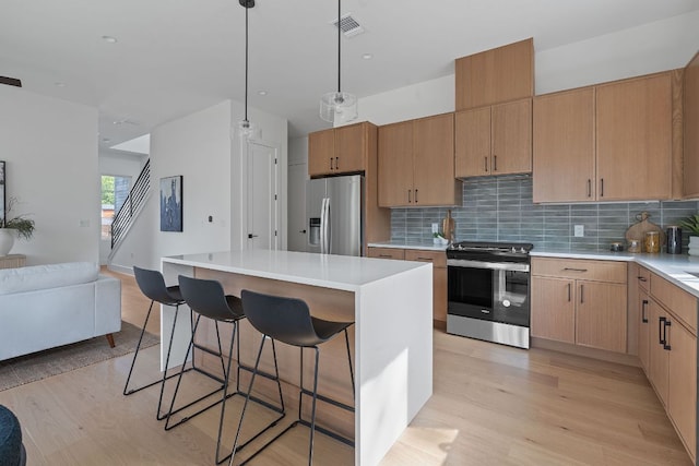 6406 Cannonleague Dr Unit 2, Austin, TX 78745 - kitchen with appliances with stainless steel finishes, light wood-type flooring, open floor plan, and a kitchen breakfast bar