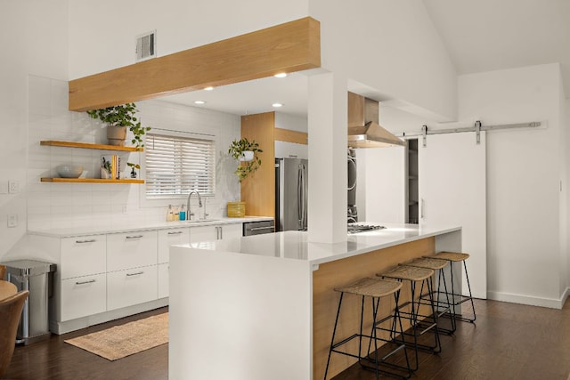 2709 Jorwoods Dr, Austin, TX 78745 - kitchen with modern cabinets, appliances with stainless steel finishes, a kitchen breakfast bar, decorative backsplash, and wall chimney range hood
