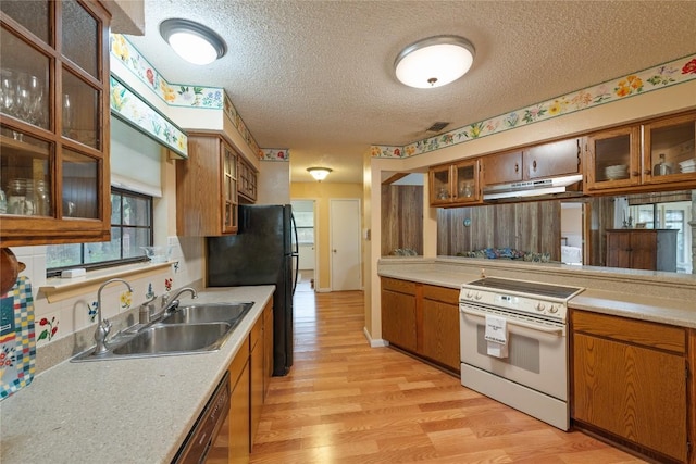 344 Fm 2984th Rd, Luling, TX 78648 - kitchen with white electric stove, brown cabinets, under cabinet range hood, a textured ceiling, and light wood-style floors