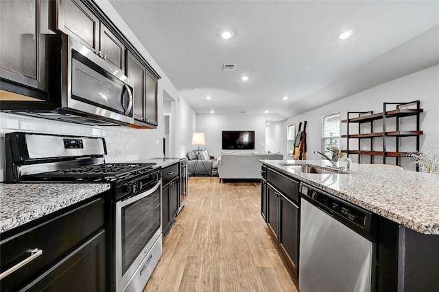 3032 Maryanne Ln, Pflugerville, TX 78660 - kitchen with stainless steel appliances, light wood-style floors, open floor plan, light stone countertops, and an island with sink
