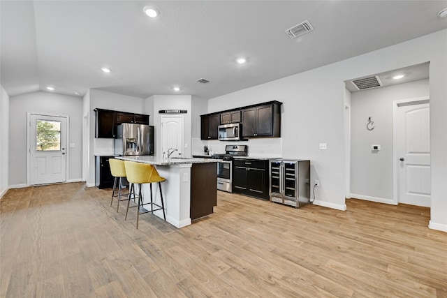 3032 Maryanne Ln, Pflugerville, TX 78660 - kitchen featuring appliances with stainless steel finishes, wine cooler, a kitchen breakfast bar, recessed lighting, and light wood-type flooring