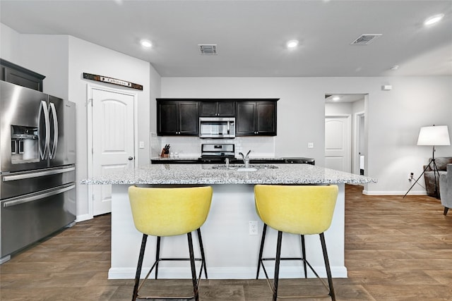 3032 Maryanne Ln, Pflugerville, TX 78660 - kitchen featuring appliances with stainless steel finishes, a breakfast bar, dark wood finished floors, an island with sink, and recessed lighting