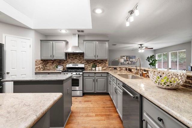 5205 Encinitas Ln, Austin, TX 78749 - kitchen featuring gray cabinets, a ceiling fan, appliances with stainless steel finishes, light wood-type flooring, and wall chimney exhaust hood
