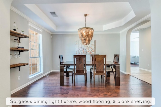 1604 Hughes Dr, Cedar Park, TX 78613 - dining space with arched walkways, a raised ceiling, plenty of natural light, dark wood-style flooring, and ornamental molding