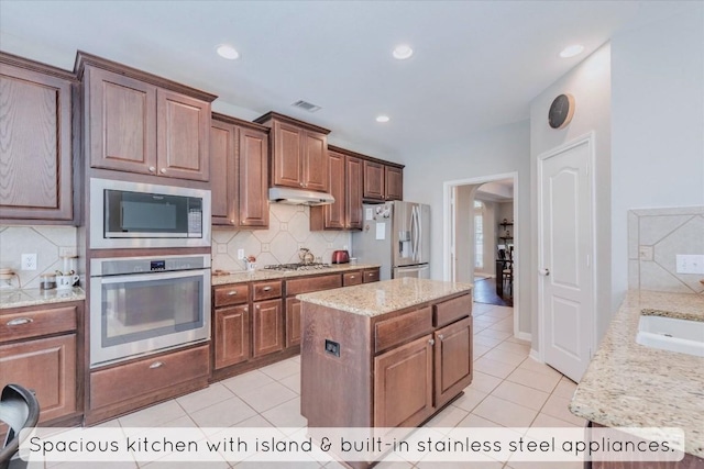 1604 Hughes Dr, Cedar Park, TX 78613 - kitchen featuring stainless steel appliances, arched walkways, light tile patterned floors, under cabinet range hood, and recessed lighting