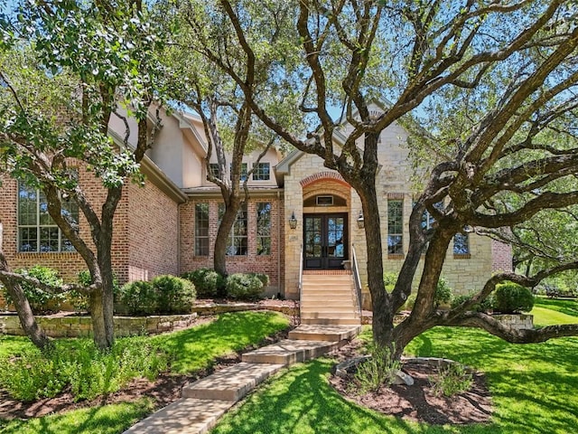 128 Squires Dr, Lakeway, TX 78734 - view of front of property with french doors, a front yard, stucco siding, stone siding, and brick siding