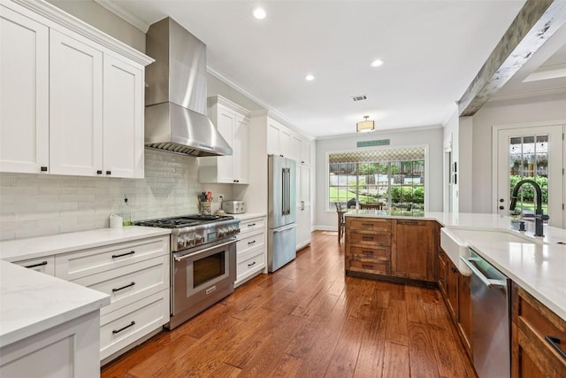 128 Squires Dr, Lakeway, TX 78734 - kitchen with high quality appliances, wall chimney exhaust hood, ornamental molding, tasteful backsplash, and dark wood-type flooring