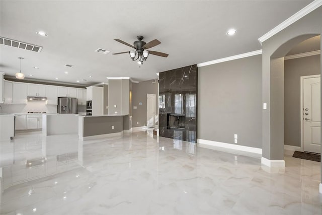 7601 Crackling Creek Dr, Austin, TX 78736 - unfurnished living room featuring arched walkways, a ceiling fan, ornamental molding, light marble finish flooring, and recessed lighting