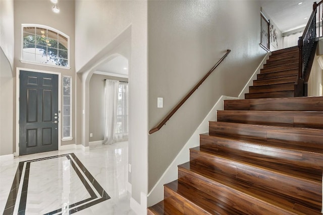 7601 Crackling Creek Dr, Austin, TX 78736 - entryway featuring a high ceiling, inlaid floor details, arched walkways, stairway, and marble tiled floors