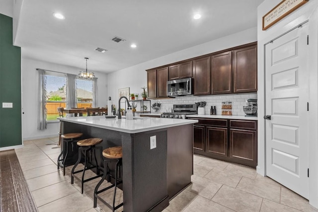 7104 Brick Slope Path, Austin, TX 78744 - kitchen featuring stainless steel appliances, backsplash, a breakfast bar, an island with sink, and light countertops