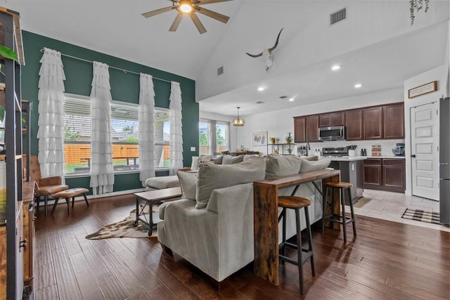 7104 Brick Slope Path, Austin, TX 78744 - living area with high vaulted ceiling, a ceiling fan, recessed lighting, dark wood-type flooring, and a chandelier