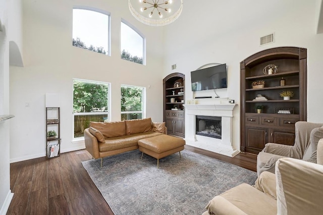 3612 Short Horn Ln, Round Rock, TX 78665 - living room with a high ceiling, a fireplace with raised hearth, dark wood-type flooring, built in features, and arched walkways